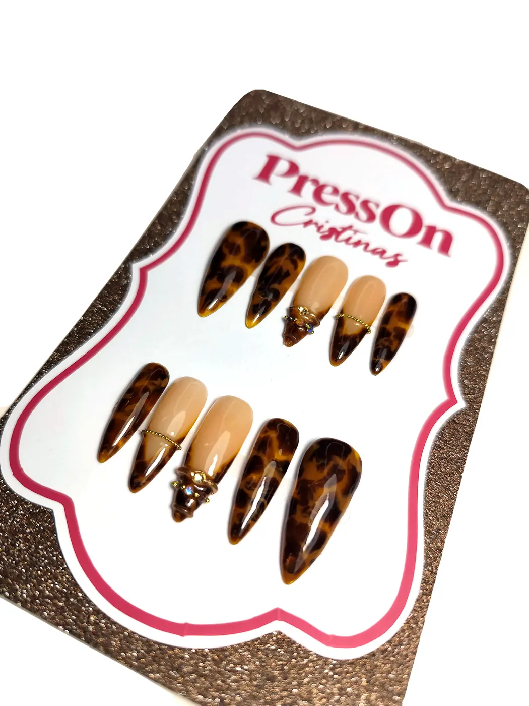 Uñas postizas stiletto con estampado carey y acento nude con charm dorado, vista en ángulo