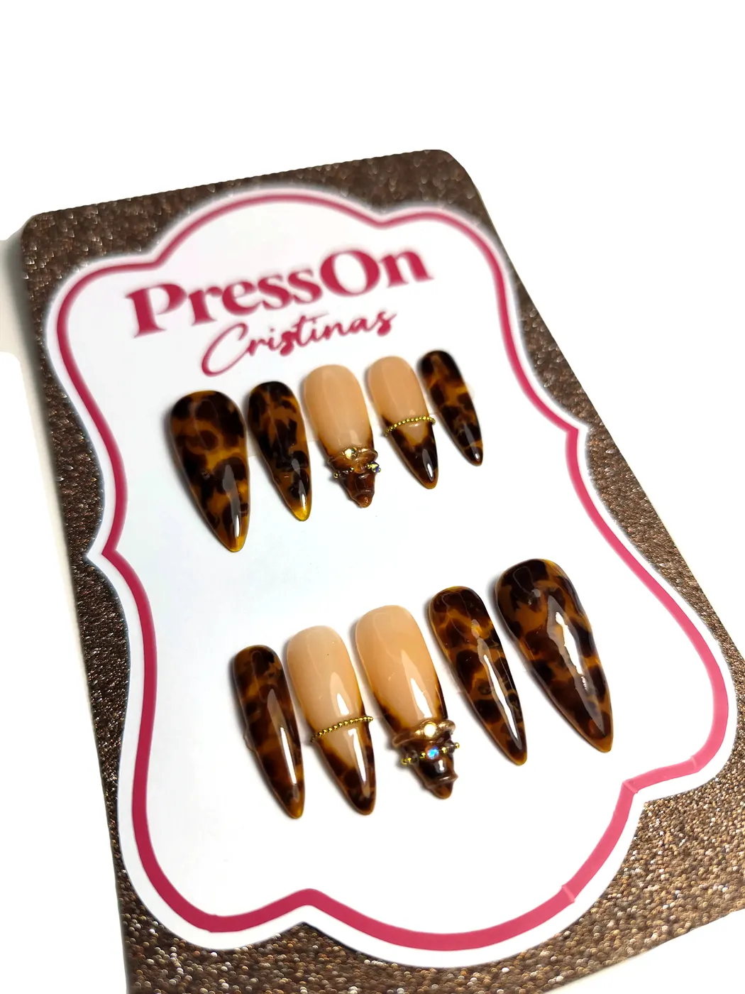 Uñas postizas stiletto con estampado carey y acento nude con charm dorado, detalle