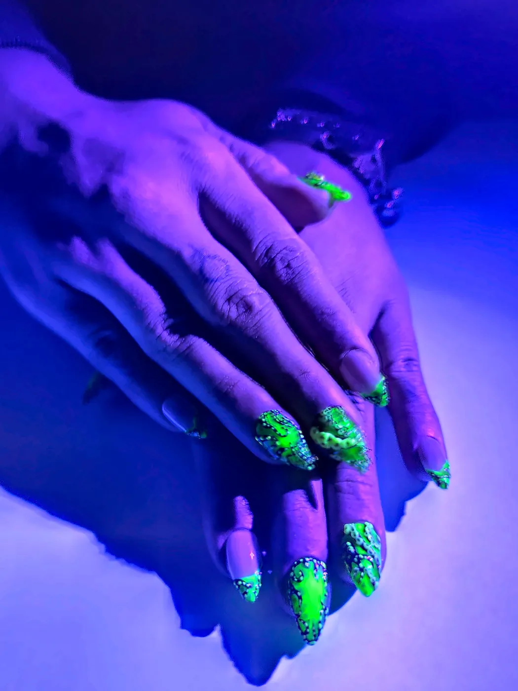 Uñas postizas almendra verdes con tentáculos de pulpo brillando bajo luz ultravioleta
