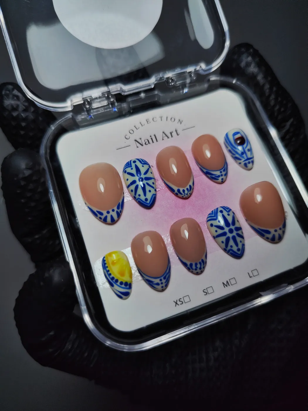 Set de uñas postizas almendra en su estuche inspirado en azulejo portugués: nude con francesa de dibujos azules, uñas con motivo de azulejo azul y blanco y una con un limón