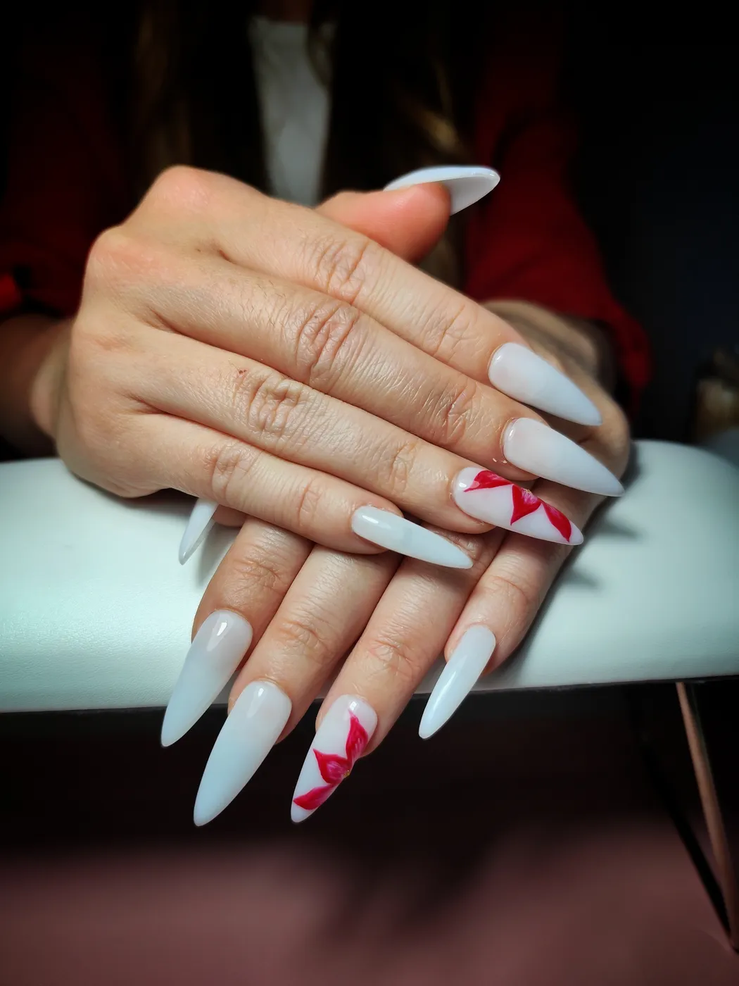 Uñas postizas stiletto largas en blanco lechoso brillante con una flor roja pintada a mano en una uña de cada mano