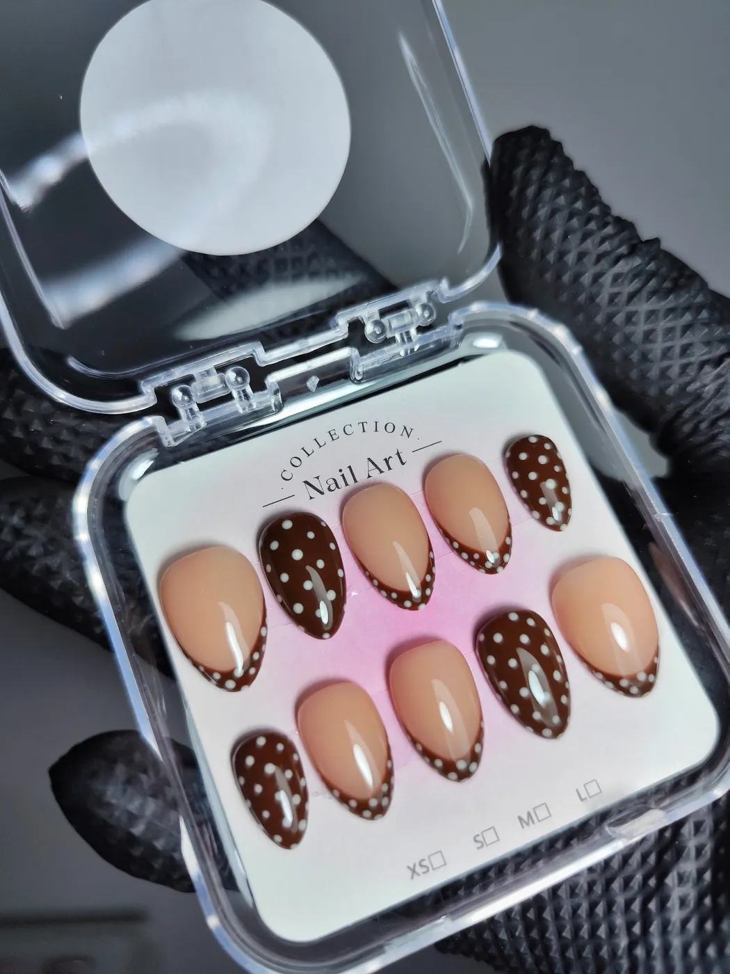 Set de uñas postizas almendra en su estuche que alterna nude con francesa marrón de lunares blancos y uñas marrón chocolate con lunares blancos