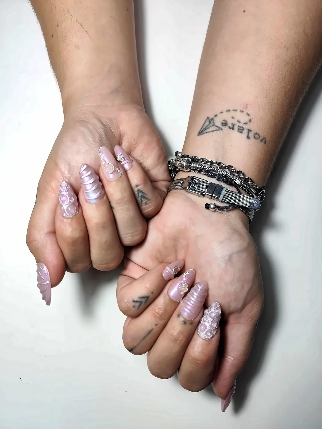 Manos con uñas postizas almendra largas en rosa nacarado con relieve 3D en forma de cuerno de unicornio